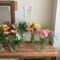 a wooden table topped with vases filled with different types of flowers and greenery