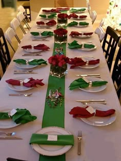 the table is set with green and red napkins, silverware, and rose centerpieces