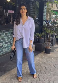 a woman standing in front of a building with her hand on her hip and smiling