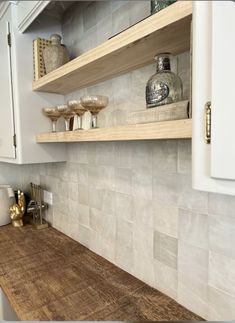 a wooden counter top in a kitchen next to white cabinets and cupboards with gold handles