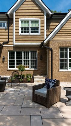 an outdoor patio with chairs and tables in front of a large brick house on a sunny day