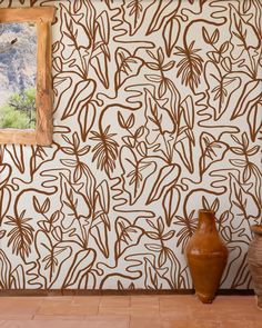 a vase sitting in front of a wall with a painting on it's side