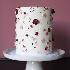 a white cake with pink and red flowers on it sitting on top of a plate