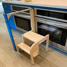 a kitchen with two ovens and a small table in front of the stove top