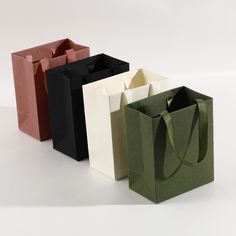 four different colored paper bags on a white surface