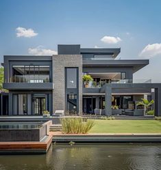 a large modern house sitting on top of a lush green field next to a body of water