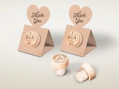 two wine bottle stoppers with corks in the shape of hearts and thank you written on them