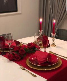 the table is set with red roses and place settings for two people to sit at