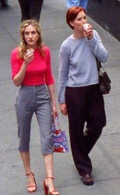 two women are walking down the street and one is holding a cell phone to her ear