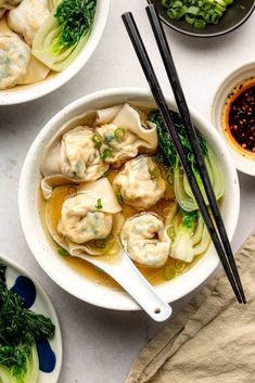 three bowls filled with dumplings and vegetables next to chopsticks on a table