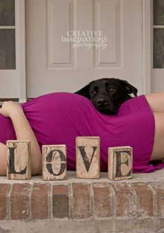 a woman laying on the ground with blocks spelling out love and a dog lying behind her