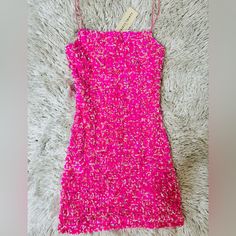 a bright pink dress is laying on a white carpet with a tag hanging from it