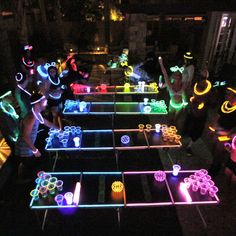 a group of people standing next to each other in front of a table with neon lights on it