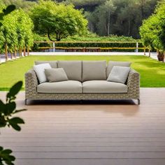 a couch sitting on top of a wooden floor next to a lush green park filled with trees