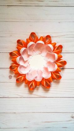 an orange and white paper flower sitting on top of a wooden table