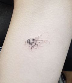 a small tattoo on the leg of a woman with a bee in it's abdomen