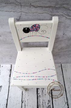 a white wooden chair with beaded trimmings and a lady bug painted on it