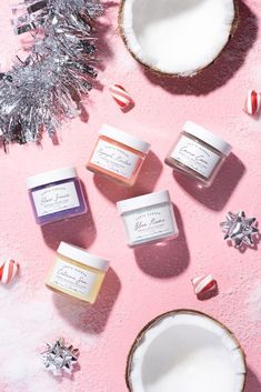 three jars of body butter sitting on top of a pink surface next to candy canes