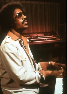 a man wearing sunglasses sitting in front of a keyboard