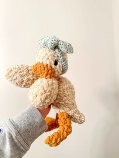 a hand holding a small stuffed bird in it's right hand and wearing a knitted hat