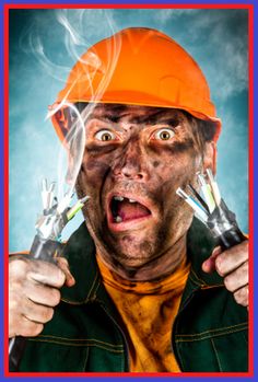 a man wearing an orange hard hat and holding two electrical wires in front of his face