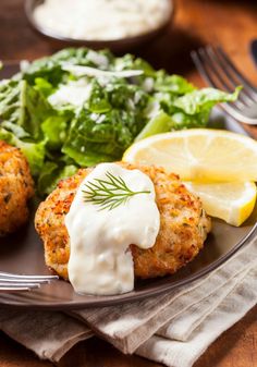 a plate with crab cakes, lettuce and lemon wedges