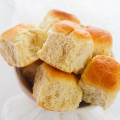 a bowl filled with rolls on top of a white table