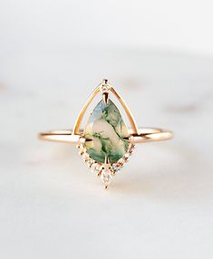 a gold ring with a green and white stone in the center