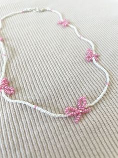 a pink and white beaded necklace on a bed