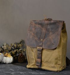 Introducing our handcrafted Rustic-Style Canvas Backpack, a perfect blend of rugged charm and functionality. This backpack is designed for those who value durability, practicality, and style. Whether you're heading out for an outdoor adventure or simply commuting to work, this backpack is your ideal companion.Key Features:- Rustic-style design with a rugged, brown leather flap closure- Secure leather buckle strap for added safety- Sturdy, tan-colored canvas material body- Padded shoulder straps Luxury Waxed Finish Leather Backpack For Outdoors, Luxury Waxed Canvas Standard Backpack, Luxury Brown Waxed Canvas Backpack, Luxury Coated Canvas Backpack With Leather Backing, Luxury Rugged Bag With Waxed Finish, Luxury Rugged Bags For Everyday Use, Luxury Brown Waxed Canvas Shoulder Bag, Luxury Rugged Leather Bag, Luxury Adventure Bag With Leather Patch