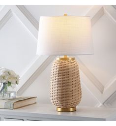 a table lamp sitting on top of a white dresser next to a vase with flowers