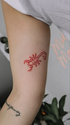 a small red scorpion tattoo on the arm