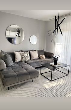 a living room with grey couches and round mirrors on the wall, along with white rugs