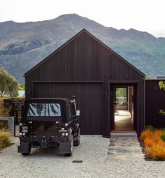 a jeep is parked in front of a black building with mountains in the background,