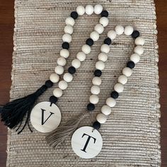 two beads with black and white tassels are on a woven place mat next to each other