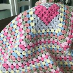 a crocheted blanket sitting on top of a table next to a vase with flowers