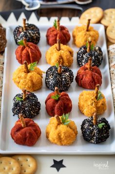 mini pumpkins and gourmet crackers on a white platter with black sprinkles