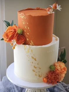 a three tiered cake with orange and white frosting, flowers on each layer