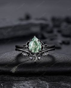 a close up view of a ring with green stone in the middle and black background