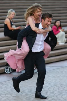 a man in a tuxedo carrying a woman on his back as they dance