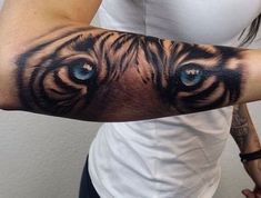 a woman's arm with a tiger face on it and blue eyes in the center