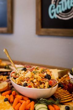 a bowl full of food sitting on top of a table next to crackers and veggies