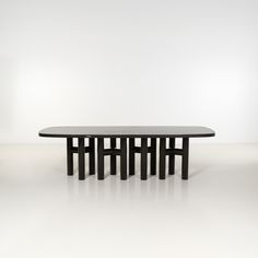 a black table with four legs on white floor and wall in the background, there is no one sitting at it