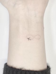 a small tattoo on the wrist of a woman with an airplane flying in the sky