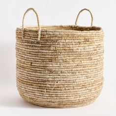 a large woven basket with two handles on the front and side, sitting against a white background