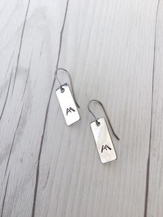 "Looking for beautiful but durable jewelry? Look no further than stainless steel! These mountain earrings are hand stamped stainless steel, with stainless steel ear wires. They won't irritate your skin like other metals can, and they won't discolor or tarnish either. Light and comfortable, these earrings won't get in your way, and will always look great. -All stainless steel -Hand stamped -3/4\" stainless steel rectangle -Gift wrapping included Customer satisfaction is my highest priority. Pleas Minimalist Stainless Steel Earrings For Gift, Everyday Stainless Steel Rectangular Jewelry, Stainless Steel Jewelry With Matching Earrings For Everyday, Everyday Dangle Earrings In Stainless Steel, Everyday Nickel Free Stainless Steel Earrings, Everyday Stainless Steel Jewelry With Matching Earrings, Everyday Stainless Steel Jewelry Set, Everyday Rectangular Stainless Steel Jewelry, Everyday Silver Surgical Steel Earrings