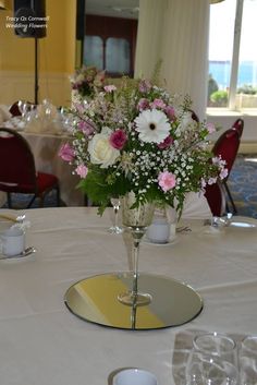 a vase with flowers on a table in a room filled with chairs and tables set up for an event