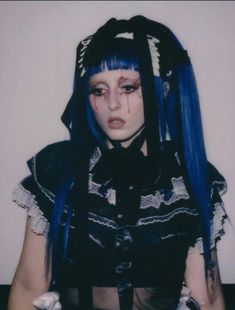 a woman with blue hair and white makeup