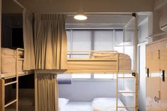 bunk beds in a small room with curtains on the windows and white sheets covering them