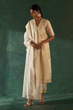 Off-white kurta with striped woven motifs and gota embellishment on shoulders. Paired with gota border embellished pant and dupatta.
Components: 3
Pattern: Woven, Embellished
Type Of Work: Striped, gota
Neckline: V neck
Sleeve Type: Half sleeves
Fabric: Kurta: Silk Tissue, Lining: Cotton, Pant: Poplin, Dupatta: Organza
Color: Off White
Other Details: 
Length:
Kurta: 48 inches
Pant: 37 inches
Dupatta Length: 90 inches
Dupatta Width: 30 inches
Occasion: Puja - Aza Fashions Striped Kurta, Tissue Dupatta, Nida Azwer, Floral Print Sarees, Geometric Texture, Dhoti Pants, White Kurta, Straight Kurta, Indian Fashion Designers